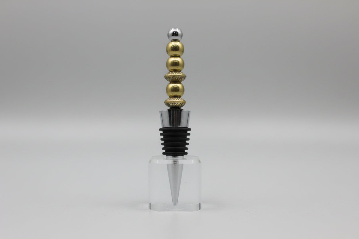 Bottle stopper with gold and silver beads on a gray background