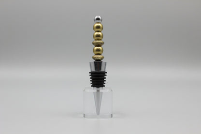 Bottle stopper with gold and silver beads on a gray background