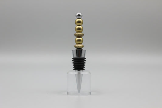 Bottle stopper with gold and silver beads on a gray background