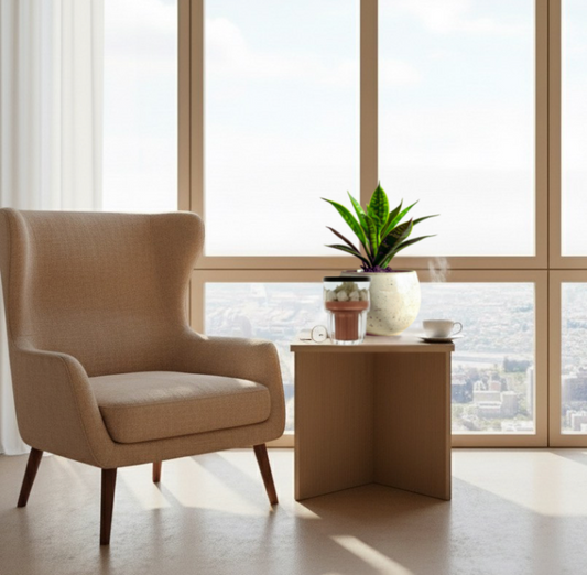 A lit Gingerbread Coffee candle on a wooden coffee table next to a warm latte.