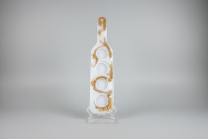 A gold resin shot glass serving paddle with slots for four shot glasses.