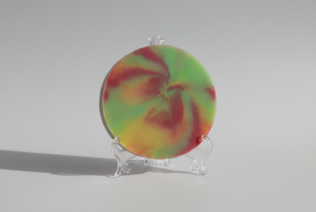 Colorful round coaster set on a stand against a gray background
